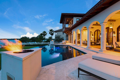 Photo of a large mediterranean backyard custom-shaped infinity pool in Miami with a water feature and brick pavers.