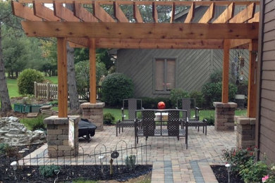 Example of a mid-sized transitional backyard concrete paver patio design with a pergola