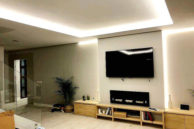 Imagen de salón abierto y beige y blanco moderno de tamaño medio de obra con paredes blancas, suelo laminado, televisor colgado en la pared y bandeja