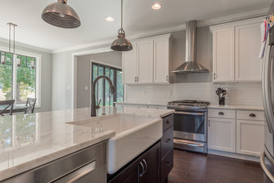 Mid-sized transitional dark wood floor eat-in kitchen photo in Other with a farmhouse sink, shaker cabinets, white cabinets, marble countertops, white backsplash, subway tile backsplash, stainless steel appliances and an island