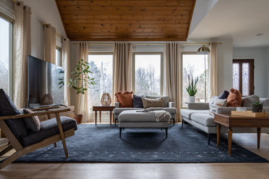 Large transitional open concept light wood floor, brown floor, vaulted ceiling and wood wall living room photo in Other with white walls, a standard fireplace, a stone fireplace and a tv stand