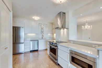 Inspiration for a mid-sized transitional u-shaped light wood floor and brown floor eat-in kitchen remodel in DC Metro with an undermount sink, recessed-panel cabinets, white cabinets, marble countertops, white backsplash, marble backsplash, stainless steel appliances and no island