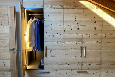 Diseño de armario unisex actual grande con armarios con paneles lisos, puertas de armario de madera clara y vigas vistas