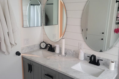 Small cottage master vinyl floor, gray floor and double-sink alcove bathtub photo in Other with shaker cabinets, gray cabinets, a two-piece toilet, white walls, an undermount sink, marble countertops, white countertops and a freestanding vanity