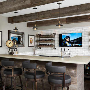 Klassisk inredning av en mellanstor u-formad hemmabar med stolar, med bänkskiva i betong, vitt stänkskydd, stänkskydd i tunnelbanekakel, mörkt trägolv och en undermonterad diskho