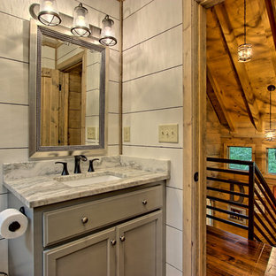Inspiration for a small rustic painted wood floor and brown floor bathroom remodel in Other with recessed-panel cabinets, gray cabinets, a two-piece toilet, white walls, a drop-in sink, granite countertops and a hinged shower door