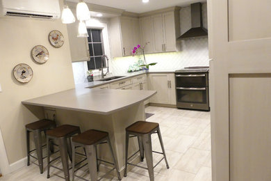 Eat-in kitchen - transitional u-shaped porcelain tile eat-in kitchen idea in New York with an undermount sink, shaker cabinets, gray cabinets, quartz countertops, white backsplash, glass tile backsplash, stainless steel appliances and a peninsula
