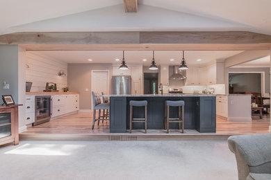 Example of a large country u-shaped light wood floor and beige floor open concept kitchen design in Detroit with an undermount sink, shaker cabinets, white cabinets, granite countertops, white backsplash, stainless steel appliances and an island