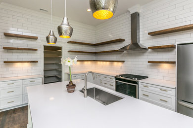 Example of a mid-sized farmhouse u-shaped dark wood floor and brown floor enclosed kitchen design in Raleigh with an undermount sink, open cabinets, medium tone wood cabinets, quartz countertops, white backsplash, subway tile backsplash, stainless steel appliances, an island and white countertops
