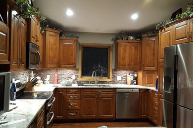 This is an example of a mid-sized traditional u-shaped kitchen in Other with dark wood cabinets, granite benchtops, with island, brown floor, a double-bowl sink, raised-panel cabinets, multi-coloured splashback, matchstick tile splashback, stainless steel appliances and dark hardwood floors.
