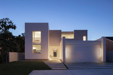 Imagen de fachada de casa blanca y blanca de tamaño medio de dos plantas con revestimiento de estuco