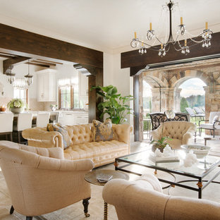 Imagen de salón abierto, mediterráneo, grande, con paredes beige, suelo de piedra caliza, chimenea tradicional, marco de chimenea de piedra y televisor colgado en la pared