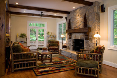 Photo of a mid-sized country open concept family room in Atlanta with beige walls, medium hardwood floors, a standard fireplace, a stone fireplace surround, no tv and brown floor.