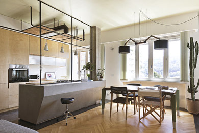 Photo of a large industrial galley eat-in kitchen in Turin with light hardwood floors, multi-coloured floor, a drop-in sink, flat-panel cabinets, light wood cabinets, stainless steel appliances, with island and grey benchtop.