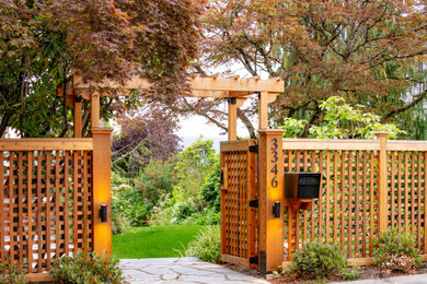 Photo of a large craftsman partial sun front yard wood fence landscaping in Seattle.
