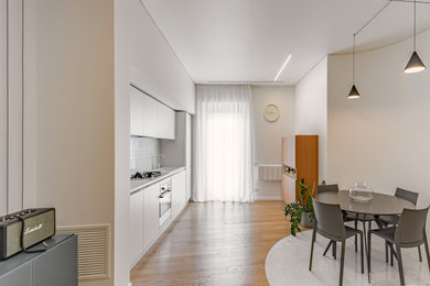 Immagine di una piccola sala da pranzo aperta verso il soggiorno contemporanea con pareti bianche e pavimento in legno massello medio