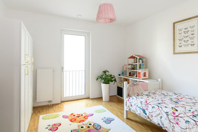 Mittelgroßes Mädchenzimmer mit Schlafplatz, weißer Wandfarbe, braunem Holzboden und braunem Boden in Sonstige