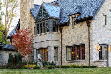 Expansive traditional two-storey beige exterior in Denver with stone veneer and a gable roof.