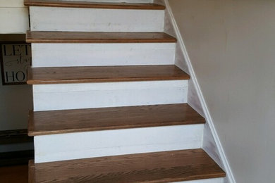 Modelo de escalera tradicional con escalones de madera, contrahuellas de madera pintada y barandilla de madera