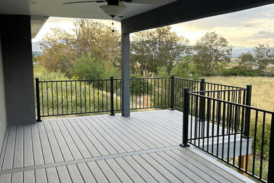 Example of a large backyard second story metal railing deck design in Salt Lake City with a roof extension