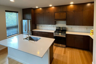 Eat-in kitchen - large contemporary galley medium tone wood floor and brown floor eat-in kitchen idea in Tampa with an undermount sink, flat-panel cabinets, dark wood cabinets, quartz countertops, white backsplash, subway tile backsplash, stainless steel appliances, an island and white countertops