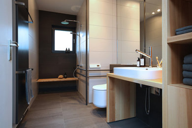 Inspiration for a mid-sized modern 3/4 bathroom in Frankfurt with open cabinets, light wood cabinets, an open shower, a wall-mount toilet, beige tile, porcelain tile, brown walls, cement tiles, a vessel sink, wood benchtops, grey floor and an open shower.