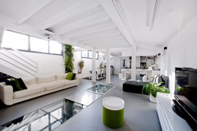 Cette image montre un grand salon design ouvert avec un mur blanc, sol en béton ciré, aucune cheminée, un sol gris et poutres apparentes.