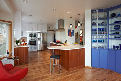 Mid-sized trendy u-shaped medium tone wood floor open concept kitchen photo in Seattle with an undermount sink, flat-panel cabinets, medium tone wood cabinets, quartz countertops, white backsplash, ceramic backsplash, stainless steel appliances and a peninsula