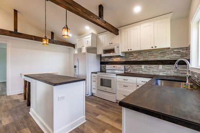 Example of a cottage kitchen design in Seattle with shaker cabinets, white cabinets, wood countertops, mosaic tile backsplash, white appliances and an island