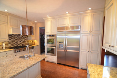Inspiration for a mid-sized transitional u-shaped medium tone wood floor and brown floor eat-in kitchen remodel in Other with an undermount sink, raised-panel cabinets, beige cabinets, granite countertops, multicolored backsplash, mosaic tile backsplash, stainless steel appliances, an island and multicolored countertops