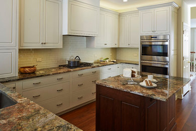 This is an example of a mid-sized transitional u-shaped separate kitchen in Chicago with a single-bowl sink, raised-panel cabinets, white cabinets, granite benchtops, white splashback, glass tile splashback, stainless steel appliances, medium hardwood floors and with island.