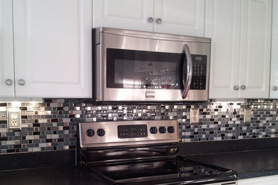 Inspiration for a contemporary kitchen remodel in Other with raised-panel cabinets, white cabinets, quartz countertops, multicolored backsplash, mosaic tile backsplash and stainless steel appliances