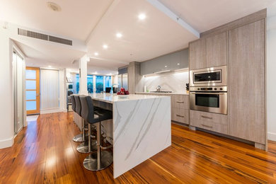 Open concept kitchen - mid-sized contemporary single-wall medium tone wood floor open concept kitchen idea in Vancouver with a double-bowl sink, flat-panel cabinets, gray cabinets, quartzite countertops, porcelain backsplash, stainless steel appliances and an island