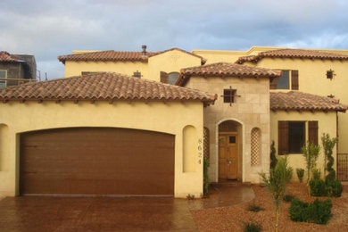 Example of a mid-sized tuscan yellow two-story mixed siding exterior home design in Albuquerque with a hip roof