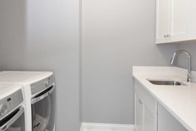 Inspiration for a mid-sized timeless galley multicolored floor laundry room remodel in Other with an undermount sink, shaker cabinets, white cabinets, quartz countertops, gray walls and a side-by-side washer/dryer