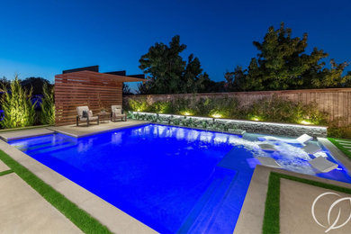 Ejemplo de piscina natural urbana de tamaño medio a medida en patio trasero con paisajismo de piscina y losas de hormigón