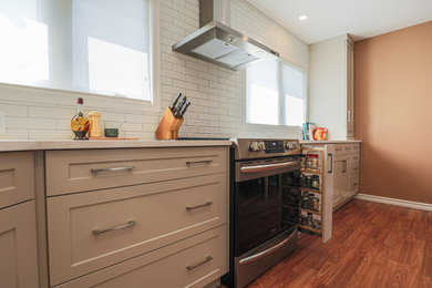Eat-in kitchen - mid-sized transitional l-shaped vinyl floor and brown floor eat-in kitchen idea in Edmonton with an undermount sink, shaker cabinets, beige cabinets, quartz countertops, white backsplash, ceramic backsplash, stainless steel appliances, no island and white countertops