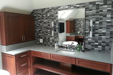 Mid-sized trendy master black tile, gray tile, white tile and glass tile bathroom photo in Cleveland with recessed-panel cabinets, medium tone wood cabinets, an undermount sink and solid surface countertops