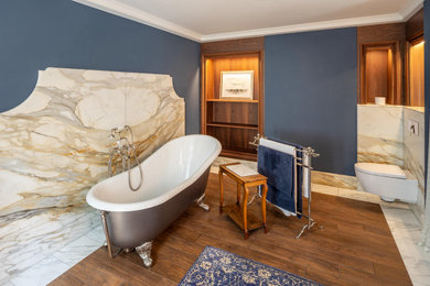 Großes Klassisches Duschbad mit braunen Schränken, freistehender Badewanne, blauer Wandfarbe, dunklem Holzboden, Unterbauwaschbecken, braunem Boden und Einzelwaschbecken in Sonstige