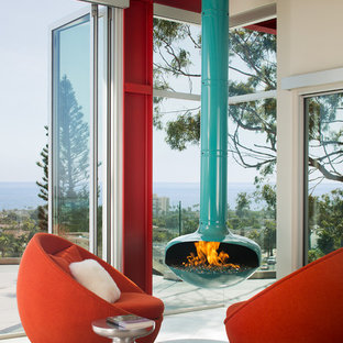 Bild på ett funkis allrum med öppen planlösning, med röda väggar, en hängande öppen spis, en spiselkrans i metall och grått golv