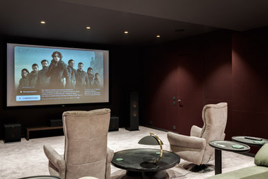 Стильный дизайн: большой изолированный домашний кинотеатр в стиле неоклассика (современная классика) с красными стенами, ковровым покрытием, проектором и бежевым полом - последний тренд