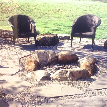 Boulder fire pit with flagstone and decorative stone.