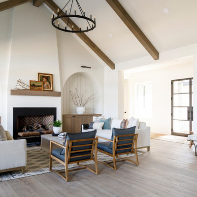 Inspiration for a mid-sized country medium tone wood floor, vaulted ceiling and shiplap wall living room remodel in Boise with white walls, a standard fireplace and a plaster fireplace