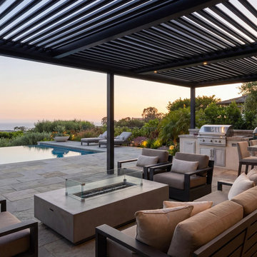 Signature Series Motorized Pergola with Outdoor Kitchen Beside an Infinity Pool