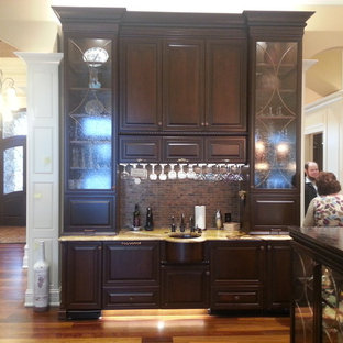 Large traditional kitchen pantry inspiration - Kitchen pantry - large traditional single-wall medium tone wood floor kitchen pantry idea in Indianapolis with an integrated sink, raised-panel cabinets, dark wood cabinets, granite countertops, brown backsplash, stone tile backsplash, paneled appliances and two islands