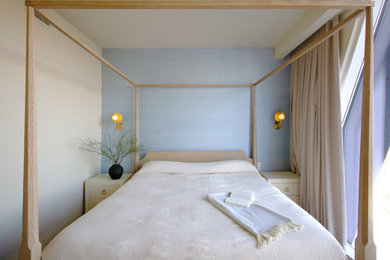 Imagen de dormitorio principal moderno con paredes azules, suelo de madera clara y papel pintado