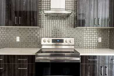 Example of a mid-sized trendy kitchen design in Edmonton with flat-panel cabinets, dark wood cabinets, metallic backsplash, stainless steel appliances and white countertops