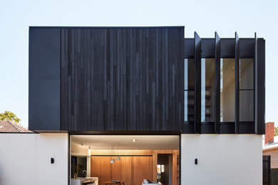 Large contemporary two-storey black house exterior in Melbourne with wood siding, a flat roof and a metal roof.