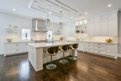 Eat-in kitchen - huge transitional galley dark wood floor and brown floor eat-in kitchen idea in New York with shaker cabinets, white cabinets, quartz countertops, white backsplash, quartz backsplash, stainless steel appliances, an island, white countertops and a drop-in sink