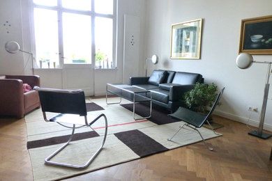 Photo of a large modern family room in Berlin with white walls and light hardwood floors.